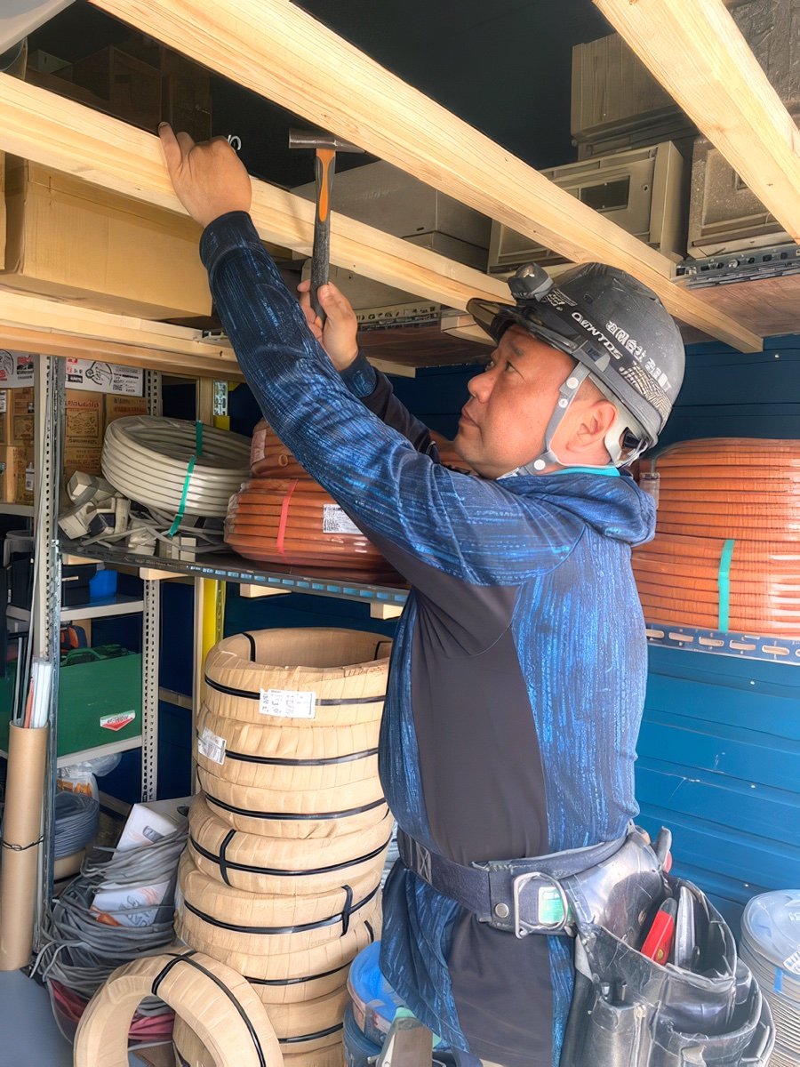 天井裏で作業する電気工事士
